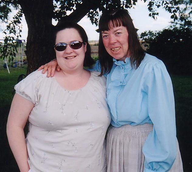 Photograph from 2001 of the author standing with her birth mother, Shirley, outdoors under a tree. They are smiling, arms around each other, dressed casually, marking one of their first meetings after years apart.