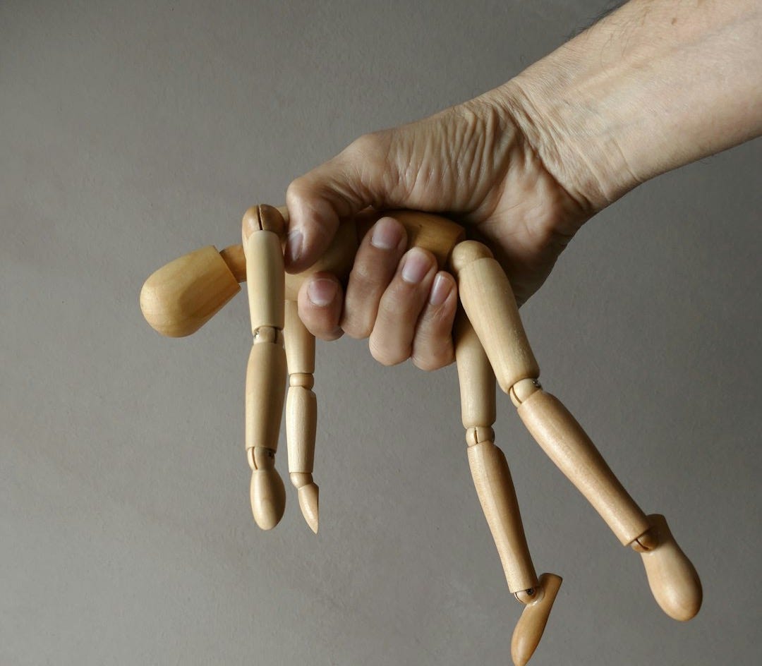 person holding brown wooden mannequin