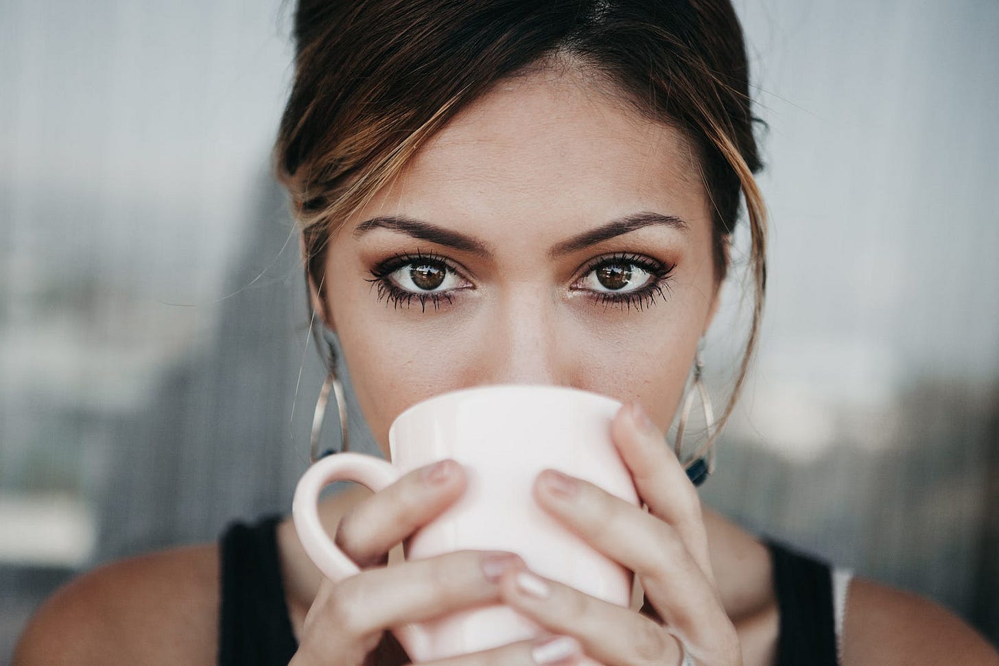 photo of woman drinking from white coffee cup