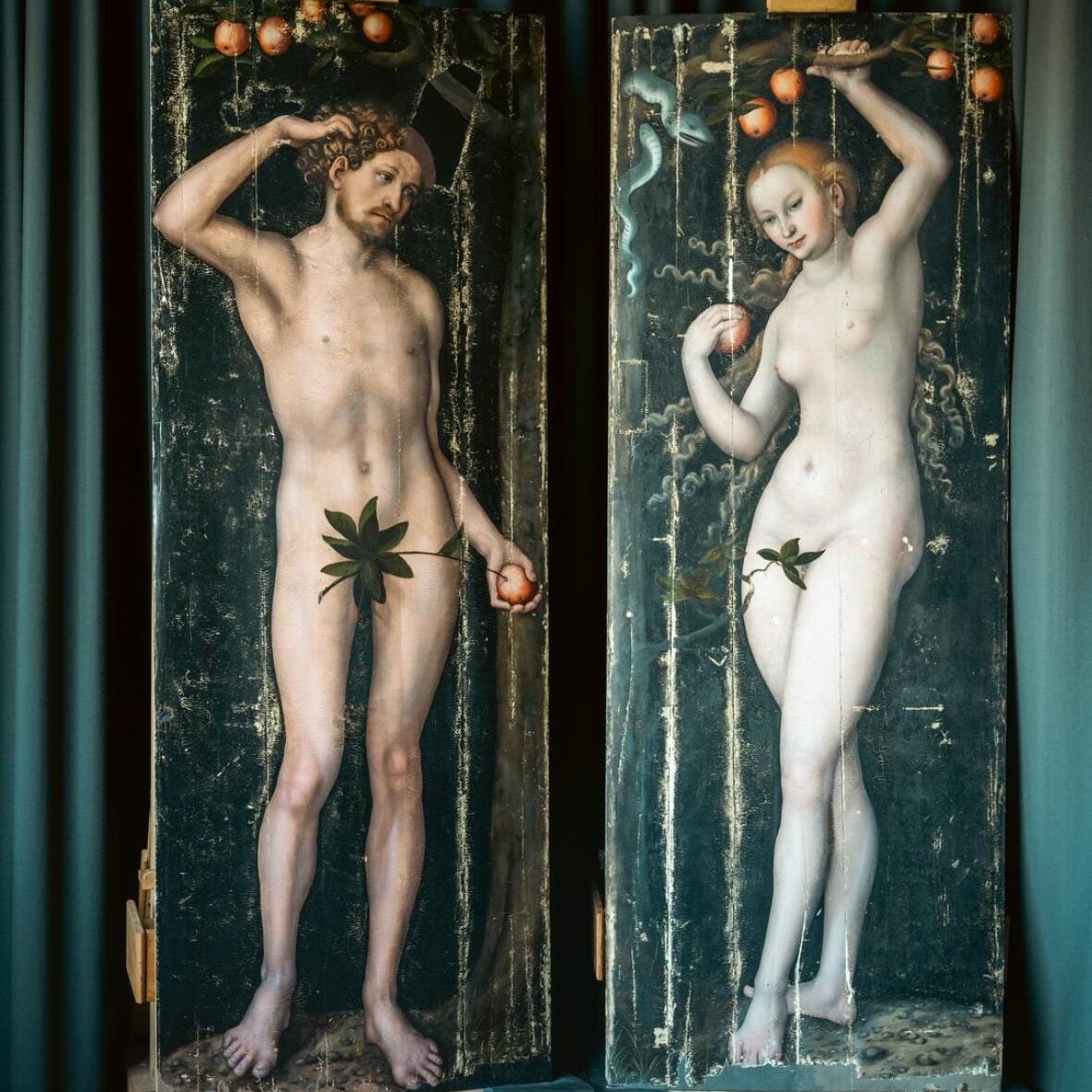 Two life-size panel paintings of naked Adam and Eve standing and holding apples. Two life-size panel paintings of naked Adam and Eve standing and holding apples.