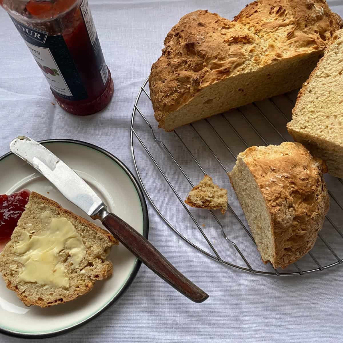 Soda Bread cut into slices. Fresh baked buttermilk soda bread, buttered and with strawberry jam.