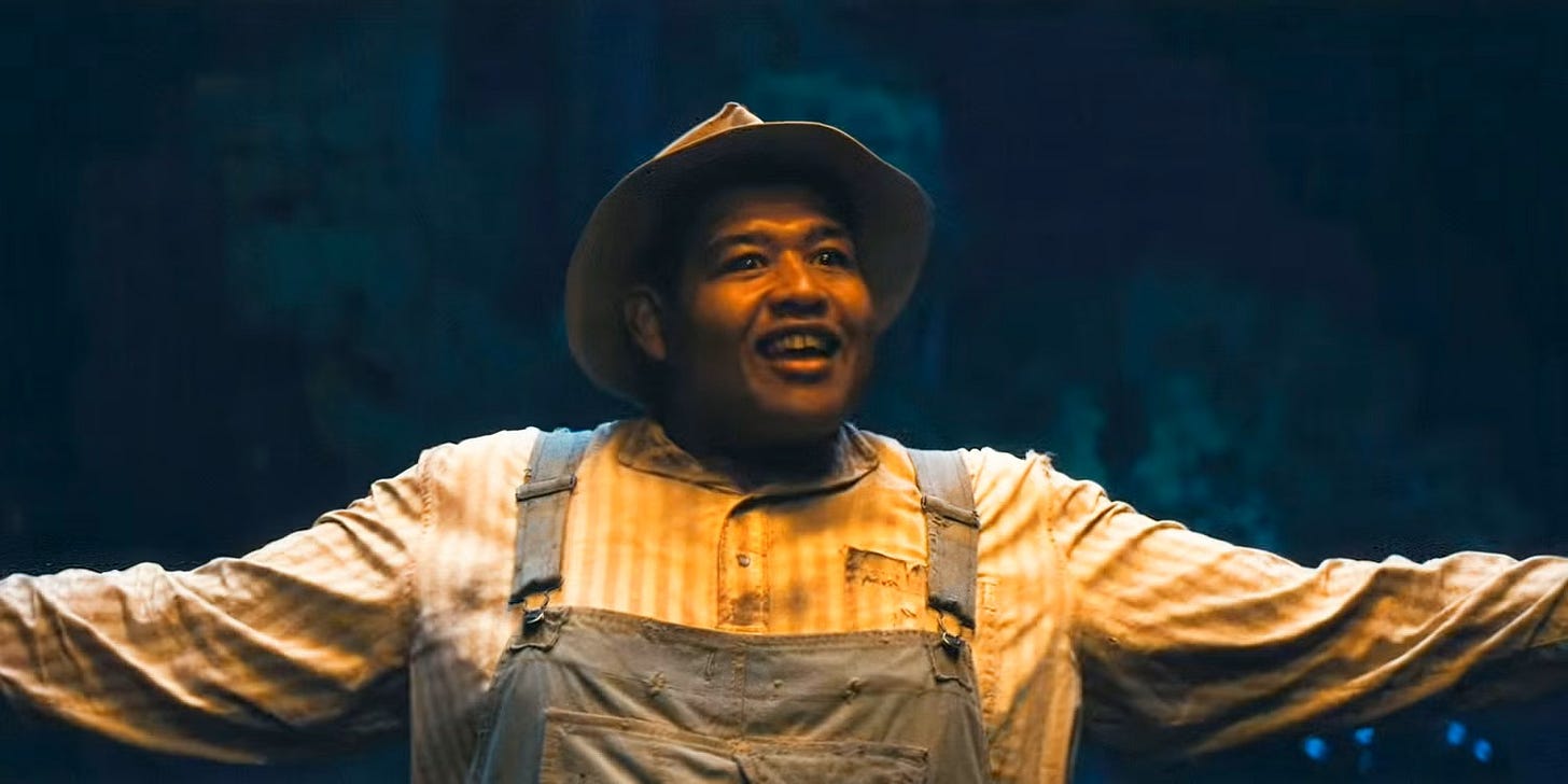 Cornbread, in the film Sinners, standing with a big smile and outstretched arms and weirdly dark eyes. Cornbread, in the film Sinners, standing with a big smile and outstretched arms and weirdly dark eyes.