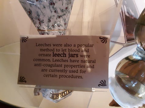Original medicines in their bottles and a small sign that sits beside the jar of leeches.