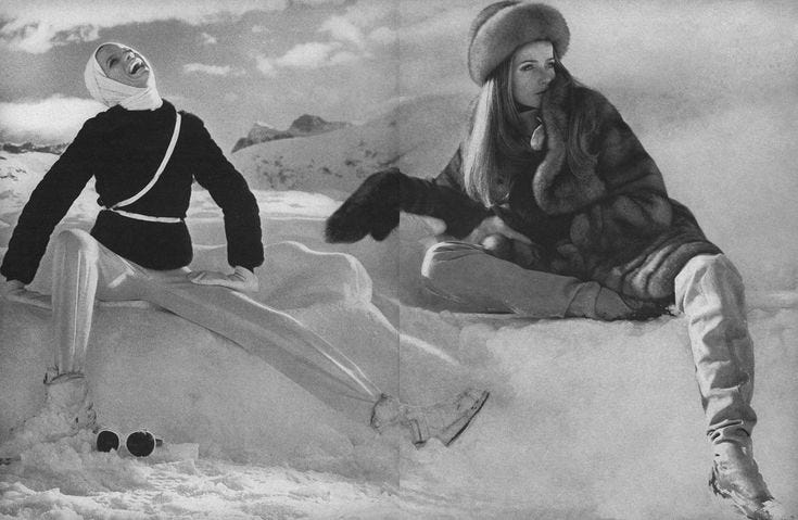 This may contain: two women sitting on top of snow covered ground next to each other in winter clothes