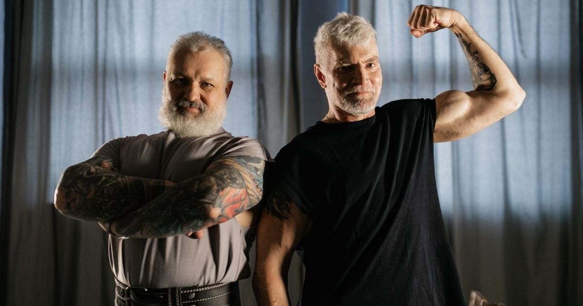 Two senior men confidently flexing and crossing arms indoors, showcasing strength and positive aging Two senior men confidently flexing and crossing arms indoors, showcasing strength and positive aging