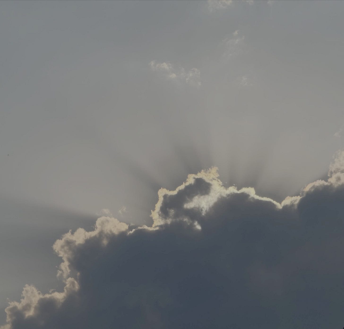 Sun’s rays peeking from behind fluffy clouds in late afternoon Sun’s rays peeking from behind fluffy clouds in late afternoon