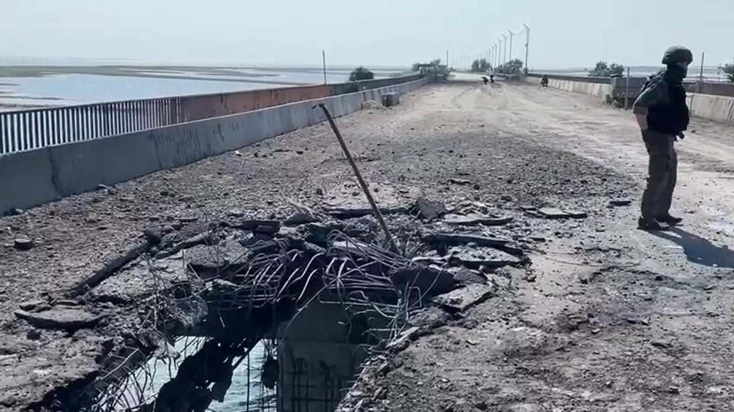 A Russian Investigative Committee serviceman stands on a bridge damaged during the Ukrainian armed forces' attack, on the administrative border between the Kherson Region and the Crimea near the village of Chongar, Crimea, Russia.  - Sputnik International, 1920, 22.06.2023