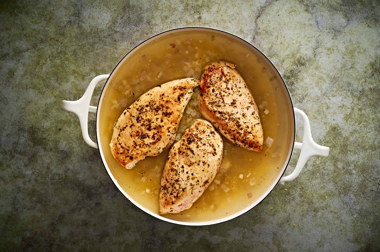 Lemon chicken orzo pasta simmering with returned chicken to the pan, uncovered.