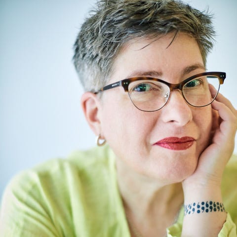 A headshot of Nan Tepper in a light green shirt, cat-eye glasses, sporting cropped salt-and-pepper hair