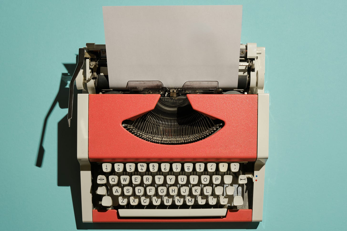 Red typewriter sitting on a blue table. 