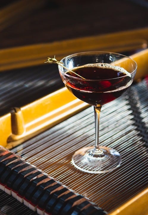 a glass of wine sitting on top of a piano a glass of wine sitting on top of a piano