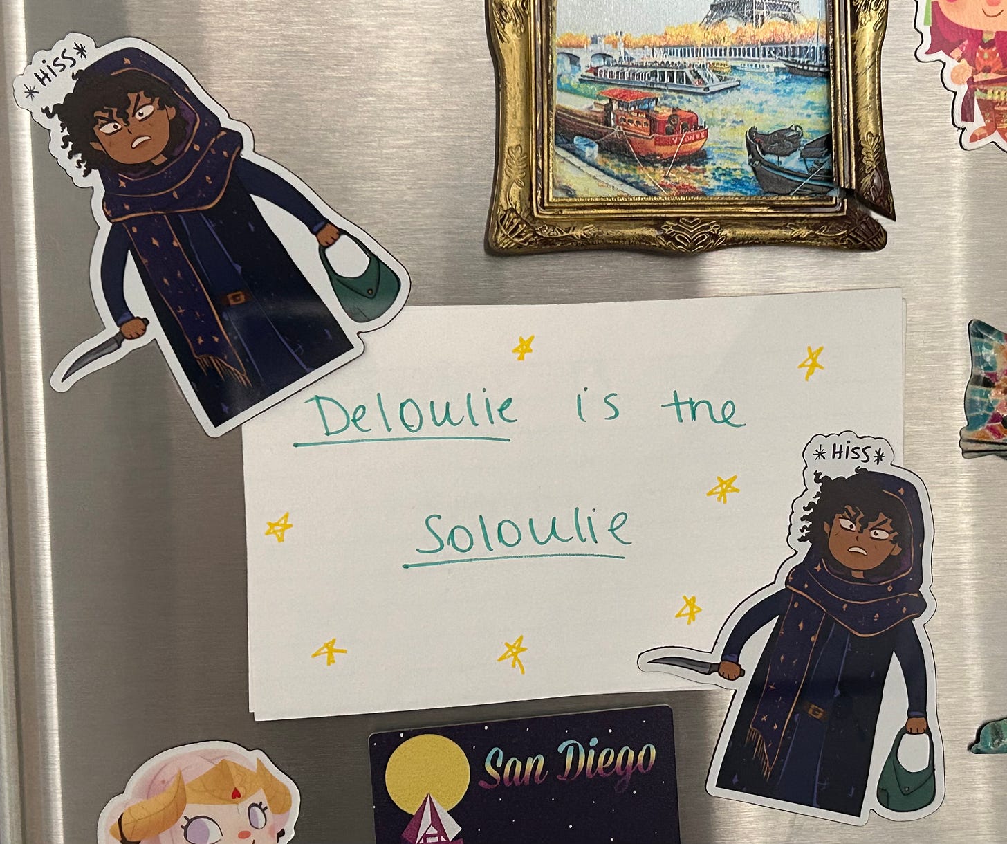 A piece of paper on the fridge that reads: "Deloulie is the soloulie" held up by two hissing Loulie magnets