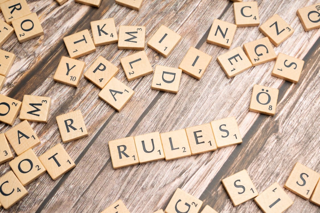 Scrabble pieces laid out on a wooden table. Four pieces spell out the word "rules". Scrabble pieces laid out on a wooden table. Four pieces spell out the word "rules".