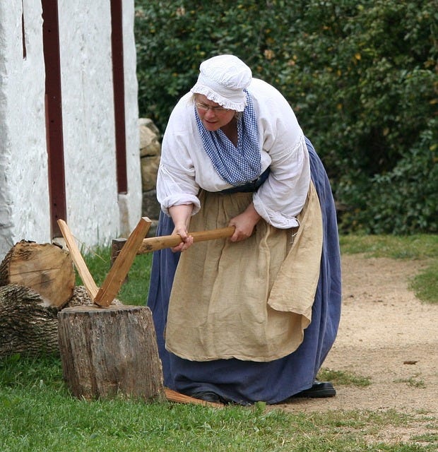 A female historical reenactor chopping wood.