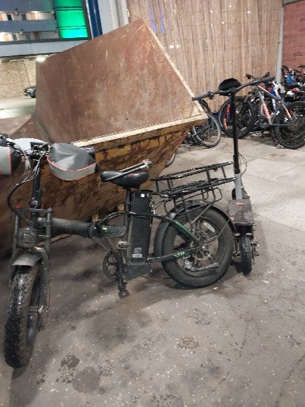 Image of an e-bike seized by police which is propped up next to a skip.