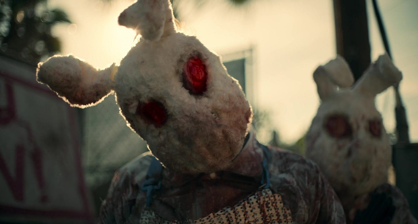 Two people in homemade rabbit masks with red eyes. One cocks his head. It's sunny out.