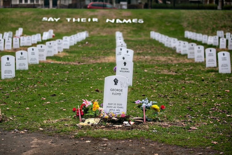 George Floyd's headstone sits front and center in an orderly faux cemetery with other white headstones set up in grass George Floyd's headstone sits front and center in an orderly faux cemetery with other white headstones set up in grass
