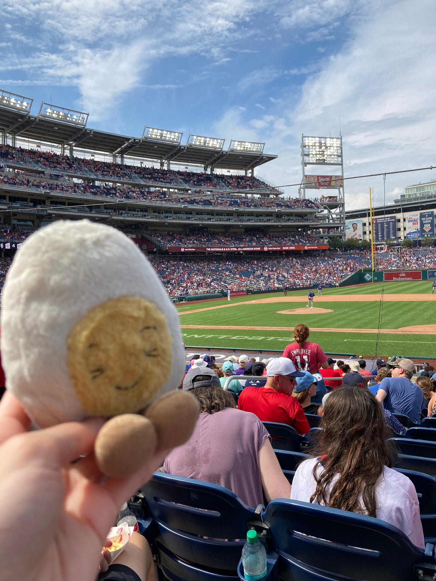 Dippy the soft toy egg at a baseball game, with a filled stadium and blue sky
