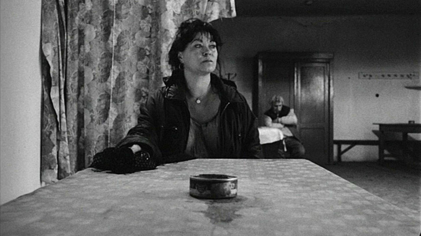 Satantango | Still features a woman sitting across the table, looking to the side.