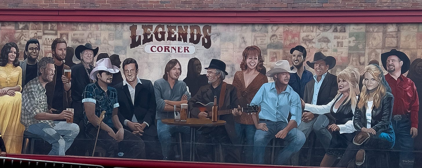 A mural of Country Legend singers on the front of a building in Nashville Tennessee. The artists include Dolly Parton, Blake Shelton, Reba McIntyre, and about ten others.