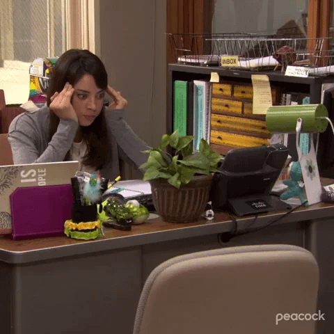 A woman sits at an office desk holding her head A woman sits at an office desk holding her head