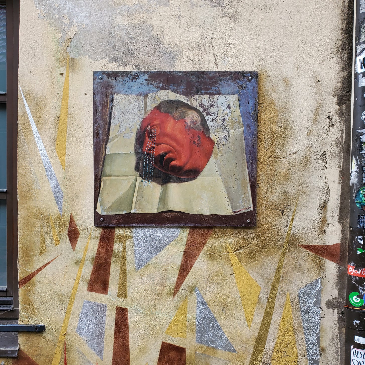 A small painting of a red-faced man crying resin tears.