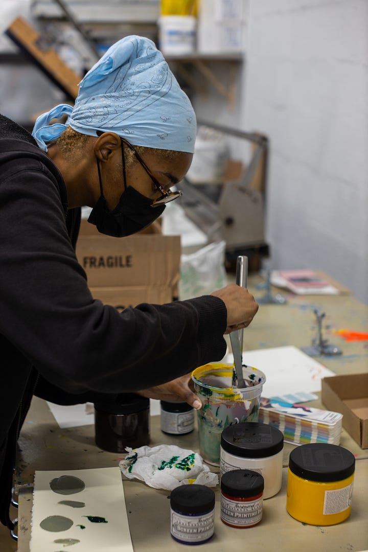 artist spraying screen for screen printing with high pressure hose mixing ink and screen printing artwork