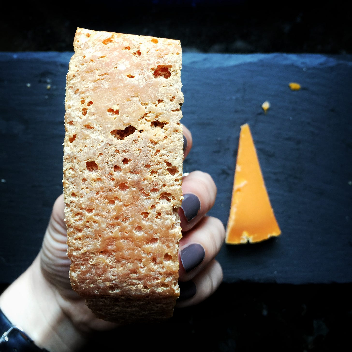 The craggy rind of a Mimolette with slices behind it