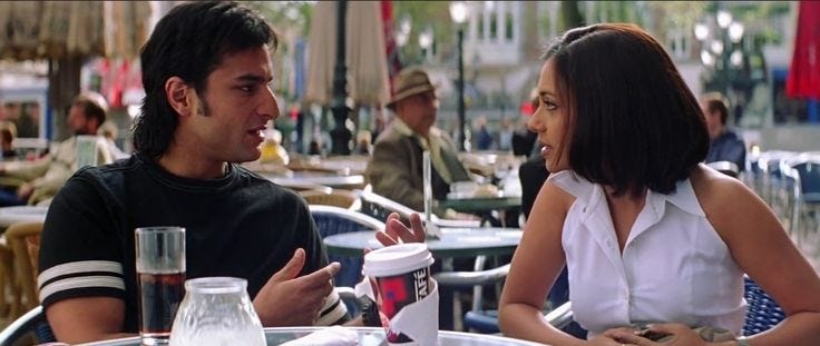 This may contain: two people sitting at an outdoor table talking This may contain: two people sitting at an outdoor table talking