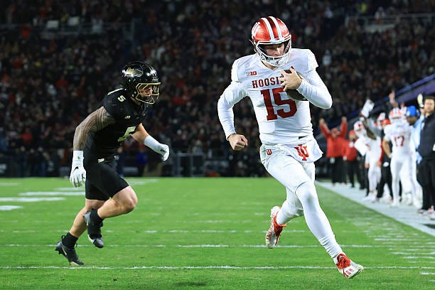 Fernando Mendoza of the Indiana Hoosiers scores a touchdown while being chased by Charles Correa of the Purdue Boilermakers at Ross-Ade Stadium on...