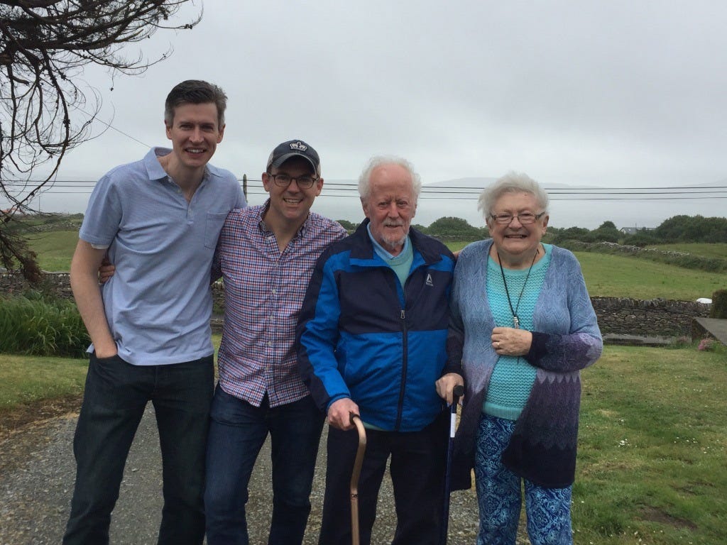 Two young men pose for picture with older man and woman outside