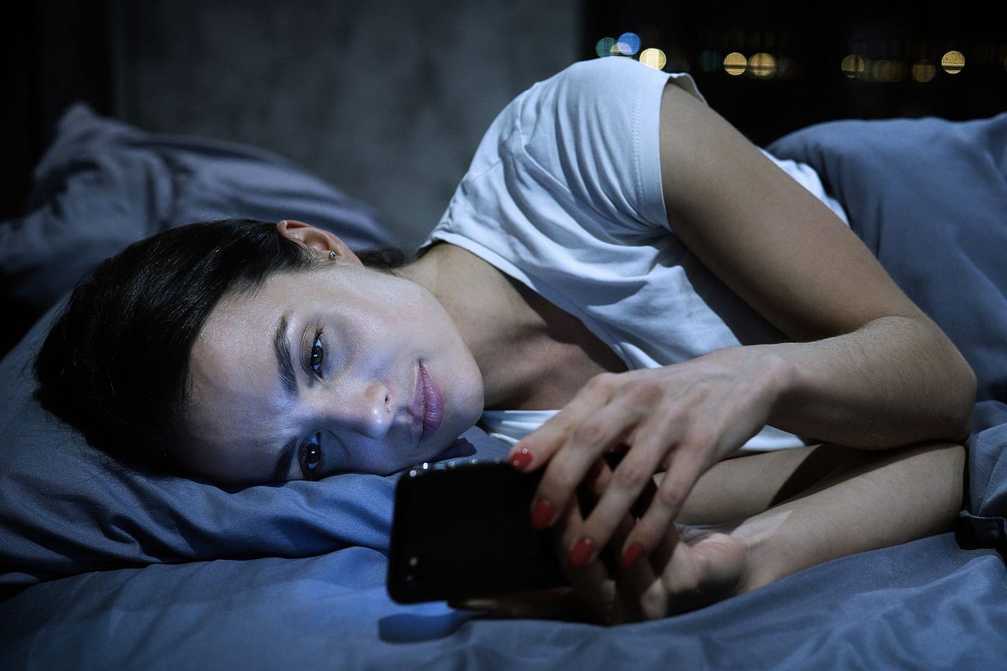 Woman in bed looking at phone.