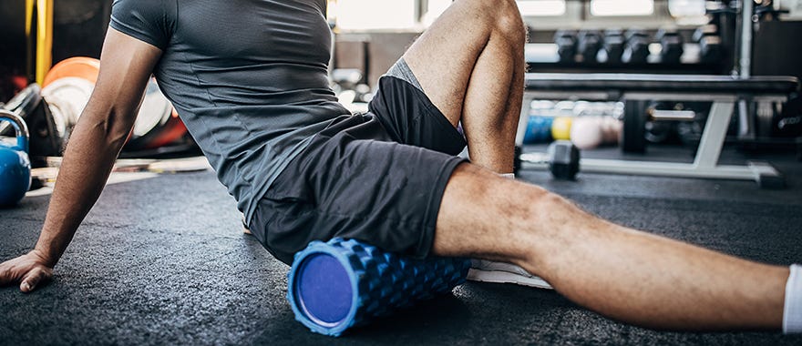 Fit male athlete foam rolling in the gym. Fit male athlete foam rolling in the gym.