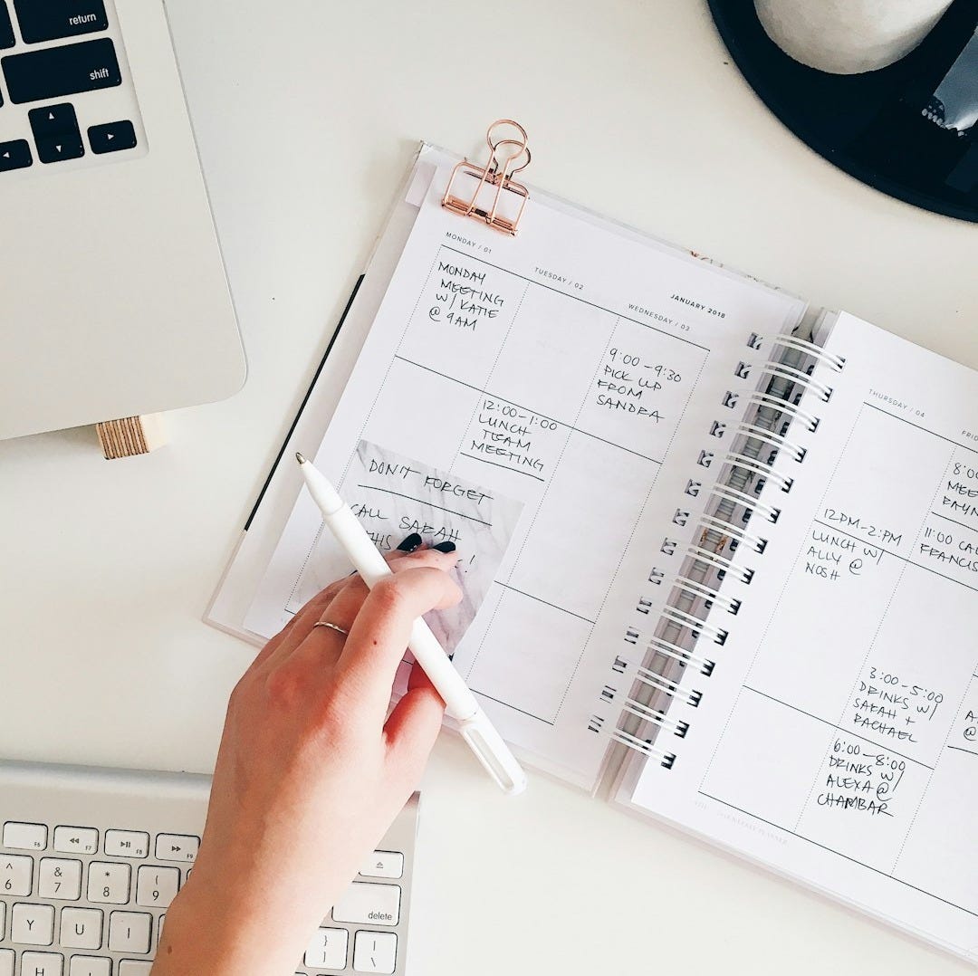 person holding notepad and pen flat lay photography
