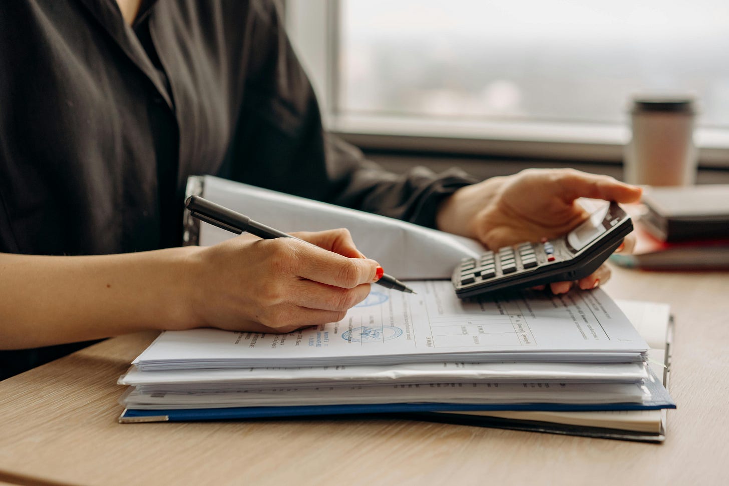 Woman with calculator and paperwork on a desk. Woman with calculator and paperwork on a desk.