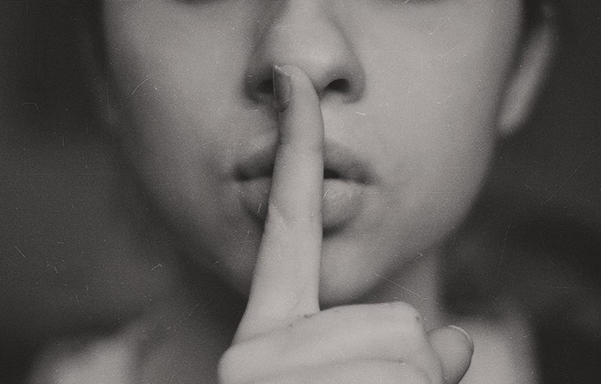 A woman with her finger against her lips, shhhh.