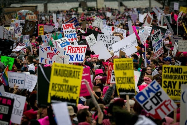 A mass of protesters hold signs that say, “Respect for All” and “Inaugurate the Resistance.”