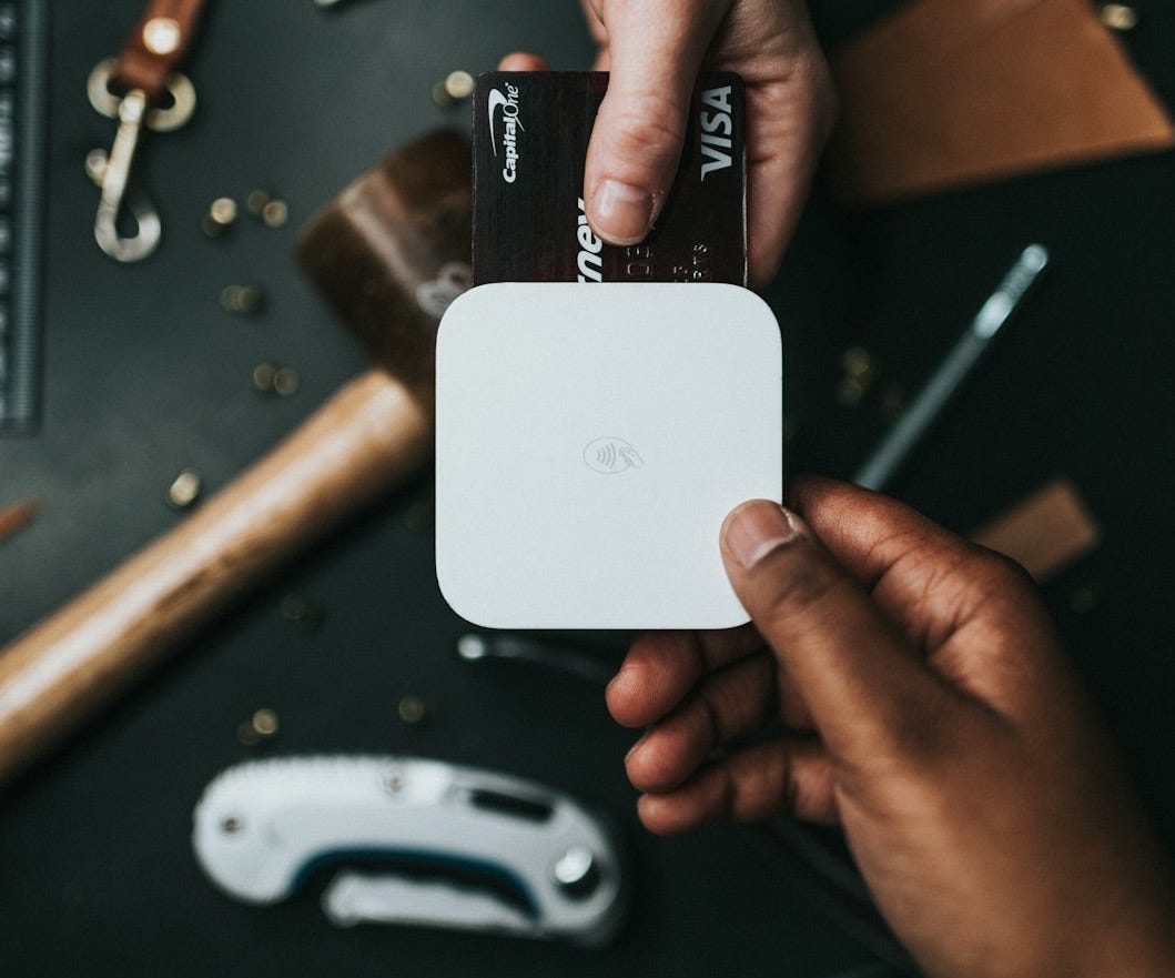 person holding Visa card and white device