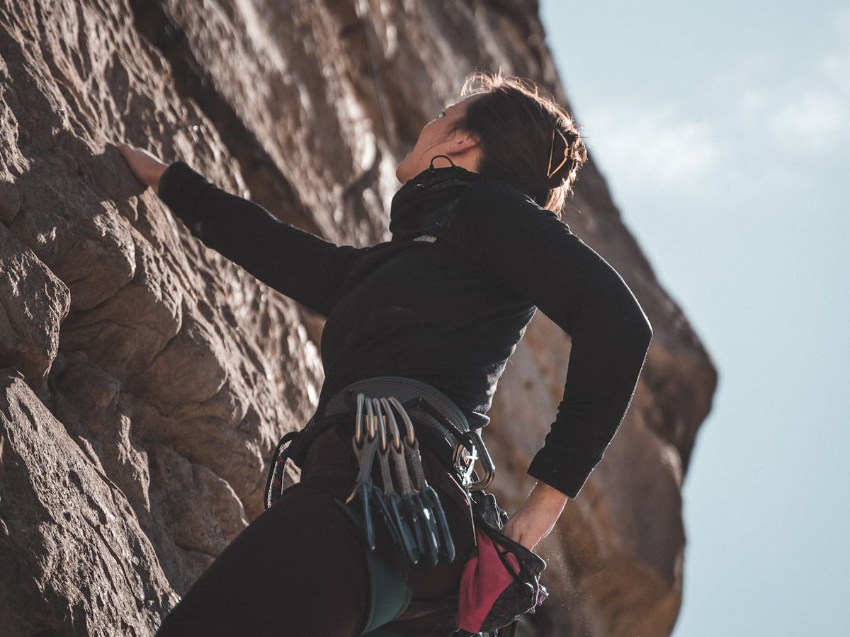 Woman free climbing a sheer rock face Woman free climbing a sheer rock face