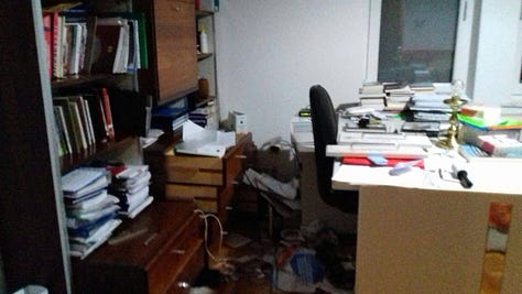 Banesa dhe biblioteka e Sadri Ramabajës pas demolimit (2016). Pamje nga brenda hapësirës së punës dhe shkallëve të banesës, të dokumentuara pas ngjarjes që ai e përshkruan si sinjal të ndjekjes së vazhdueshme. Fotot janë huazuar nga Sadri Ramabaja.