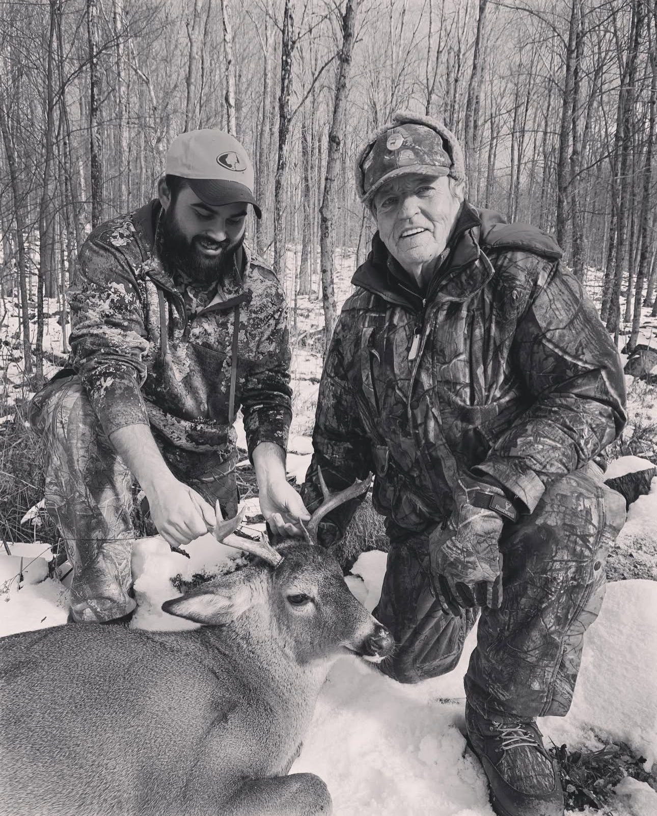 Two hunters in the woods with a deer Two hunters in the woods with a deer