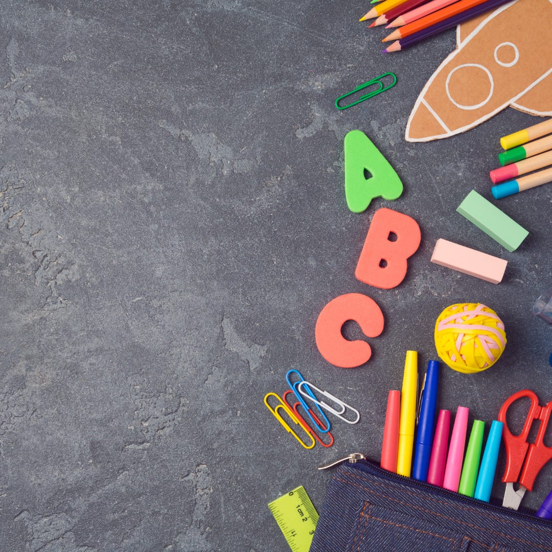 A photo with a grey work top covered with a mix of school supplies along the right side of the image. Supplies include markers, scissors, coloured pencils and paper clips. A photo with a grey work top covered with a mix of school supplies along the right side of the image. Supplies include markers, scissors, coloured pencils and paper clips.