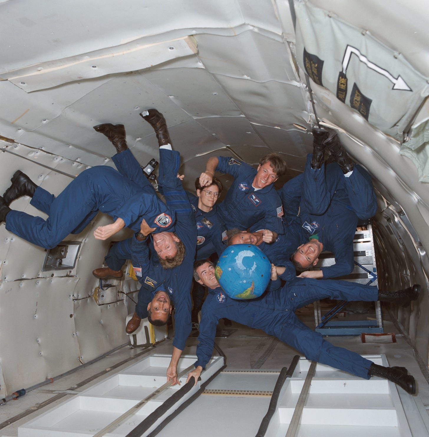 The crew of STS-45 is already training for its March 1992 mission, including stints on the KC-135 zero-gravity-simulating aircraft. Shown with an inflatable globe are, clockwise from the top, C. Michael Foale, mission specialist; Dirk Frimout, payload specialist; Brian Duffy, pilot; Charles R. (Rick) Chappell, backup payload specialist; Charles F. Bolden, mission commander; Byron K. Lichtenberg, payload specialist; and Kathryn D. Sullivan, payload commander. NASA/JSC, Public domain