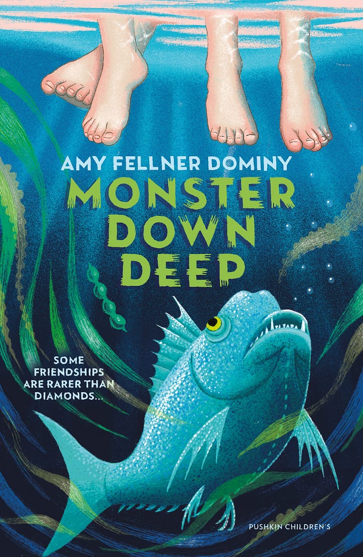 Picture of Amy Fellner Dominy smiling towards the camera with her arms crossed in front of her. Cover of Monster Down Deep which is aquatic in colour - lots of blue, green and turquoise. There's a sharp-toothed fish looking up at 3 dangling human feet.