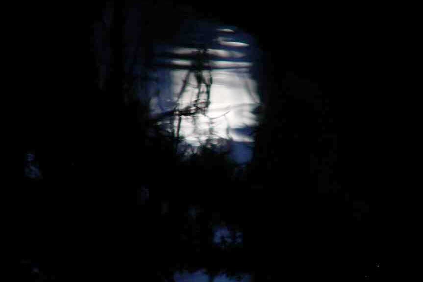 A ripply image of the moon is reflected on the surface of dark water. A ripply image of the moon is reflected on the surface of dark water.