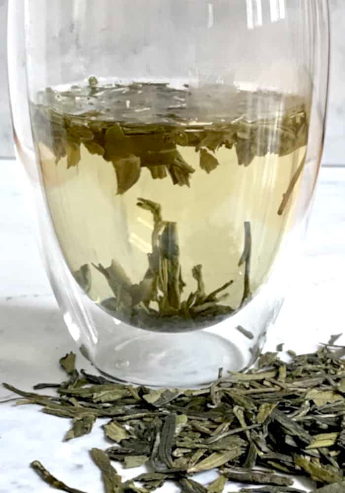 dragon well tea leaves brewing in glass
