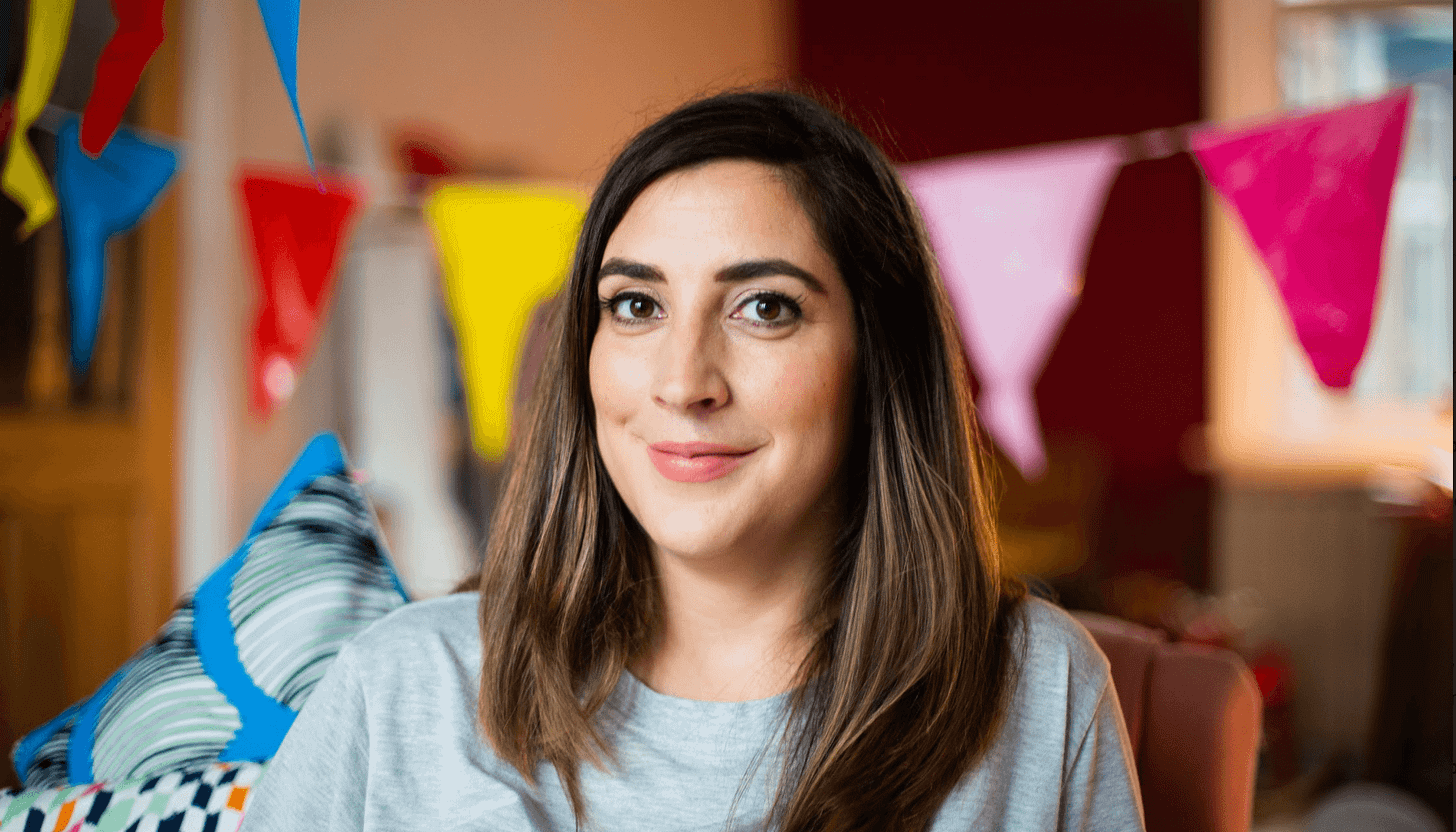 Portrait of PR strategist and author Lucy Werner smiling indoors with colourful bunting behind her