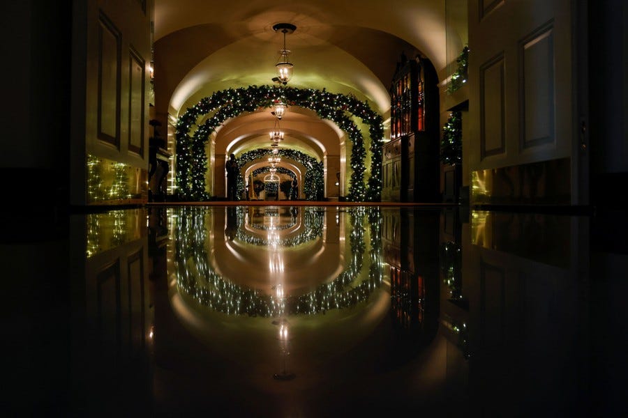 A dark hallway is lit by Christmas lights on decorations.