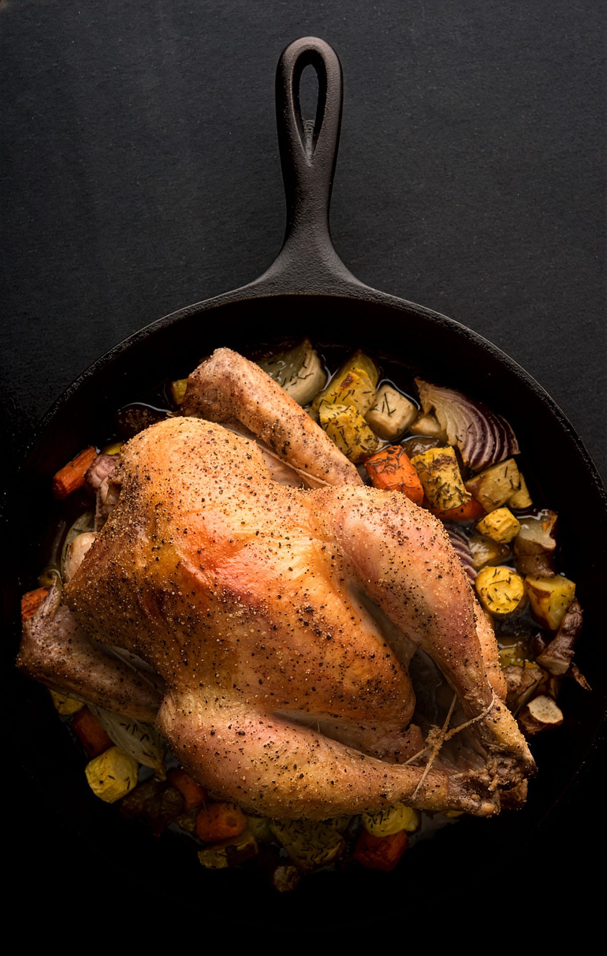 A roast chicken in a cast iron frying pan. 