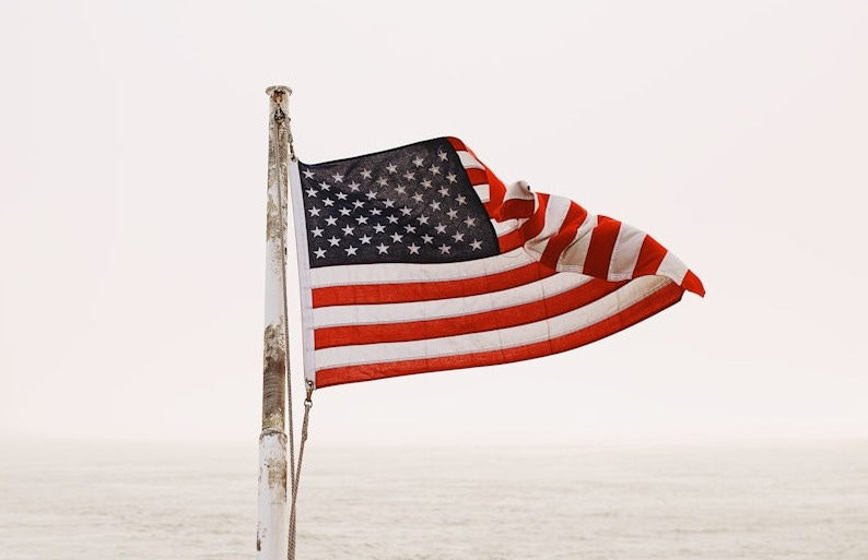 us a flag on white pole on white sand during daytime